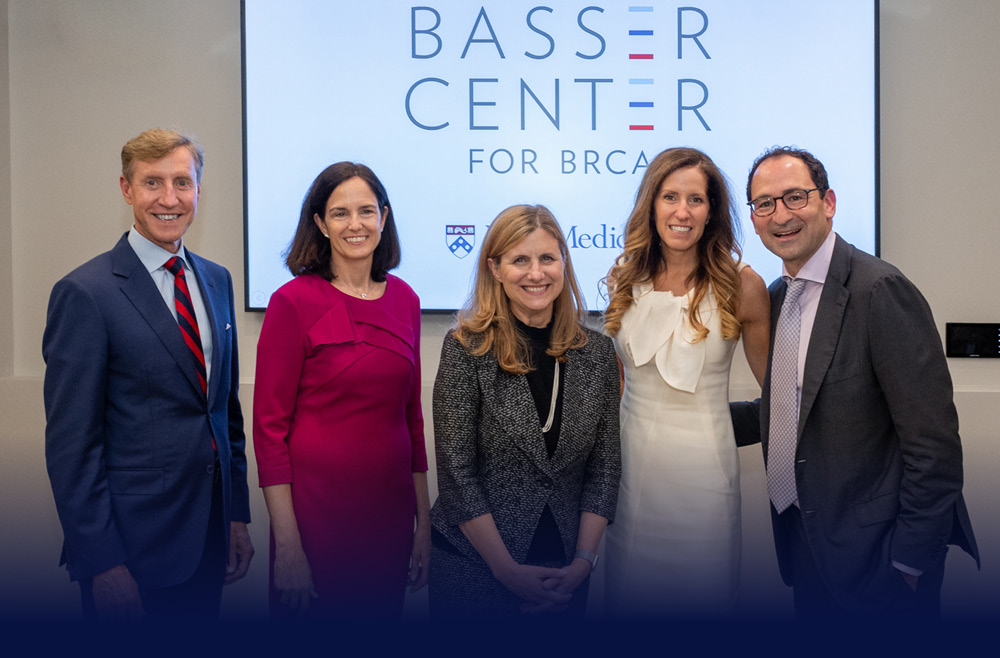A group of five people poses in front of a screen with the words “Basser Center for BRCA” displayed.